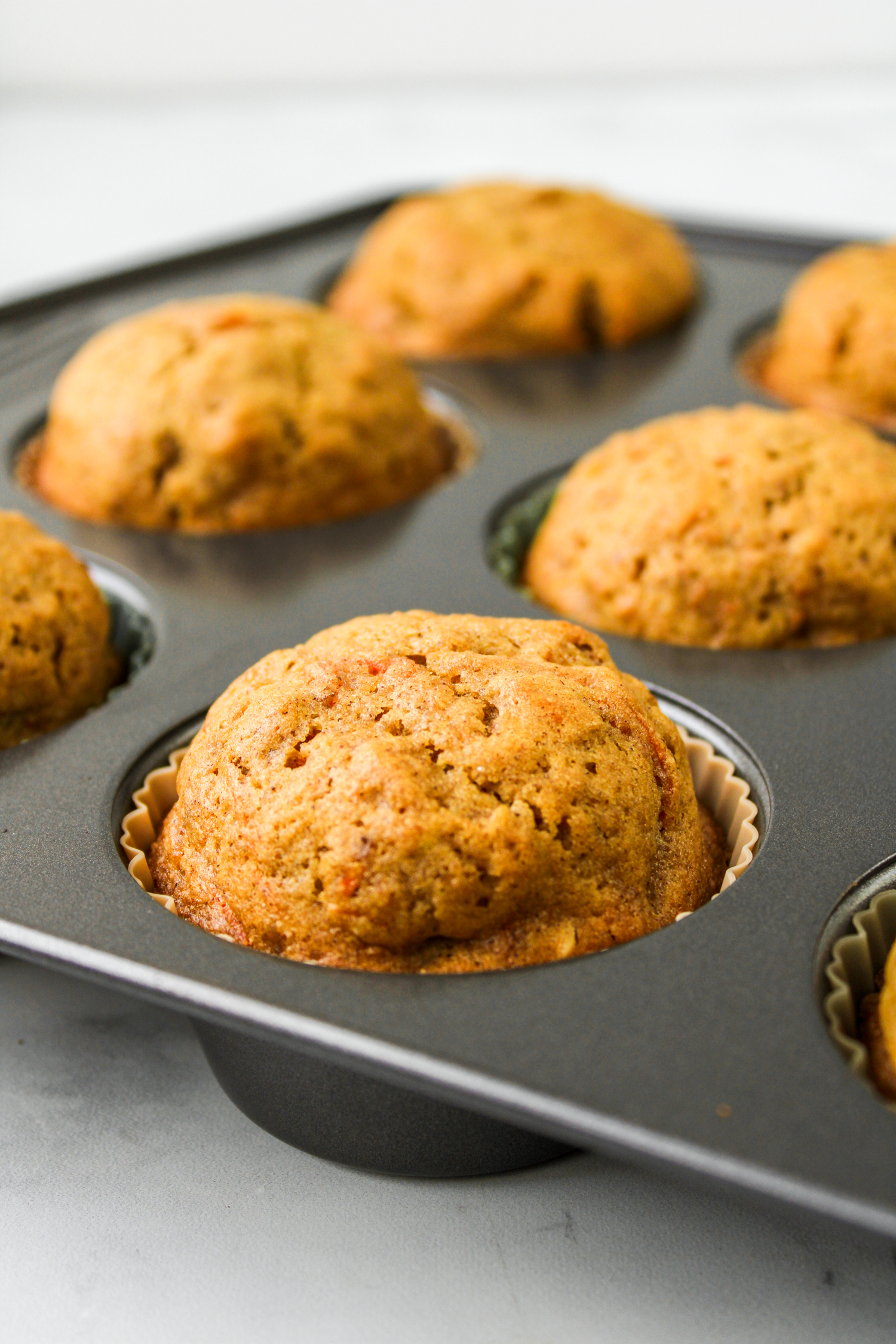 side profile shot of baked carrot apple muffins in the baking pan