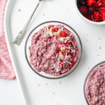 raspberry coconut oatmeal in a glass bowl on top of a white ceramic serving platter