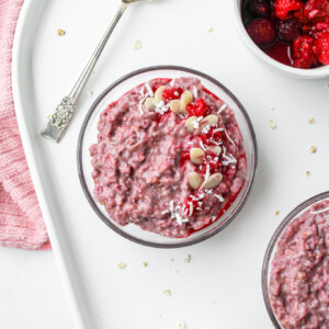 raspberry coconut oatmeal in a glass bowl on top of a white ceramic serving platter