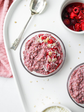 raspberry coconut oatmeal in a glass bowl on top of a white ceramic serving platter