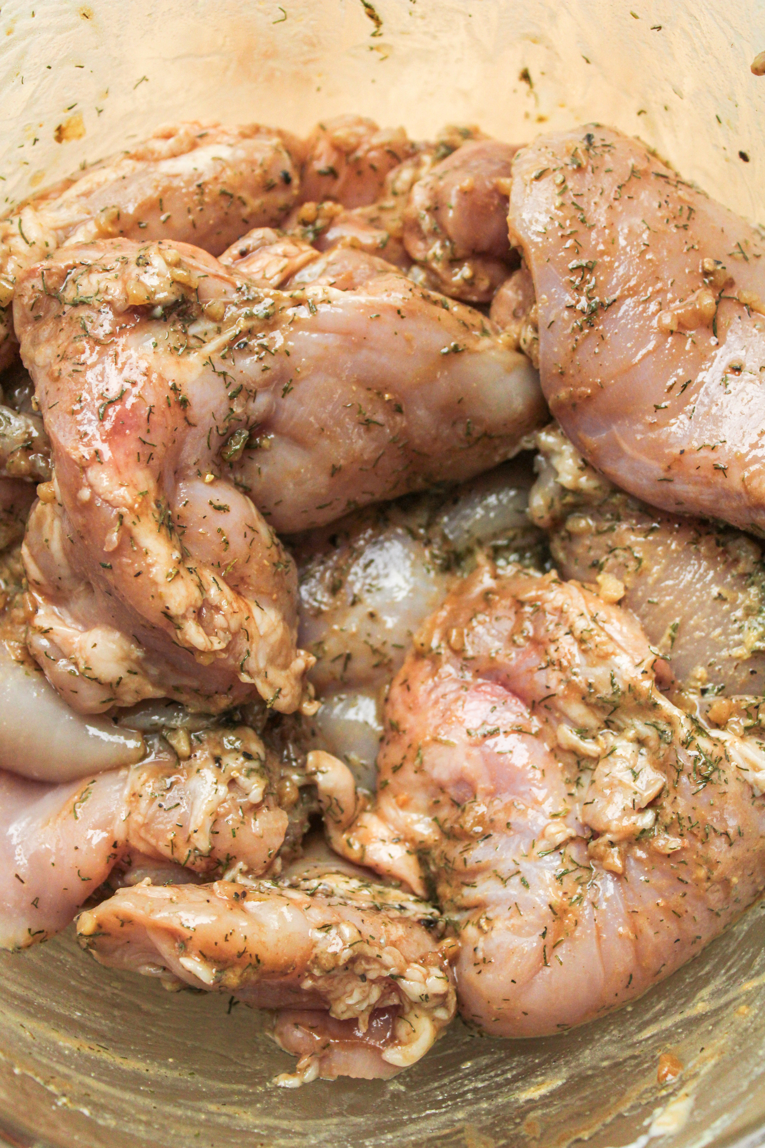 raw chicken thighs marinated in balsamic dill seasoning in a large glass bowl