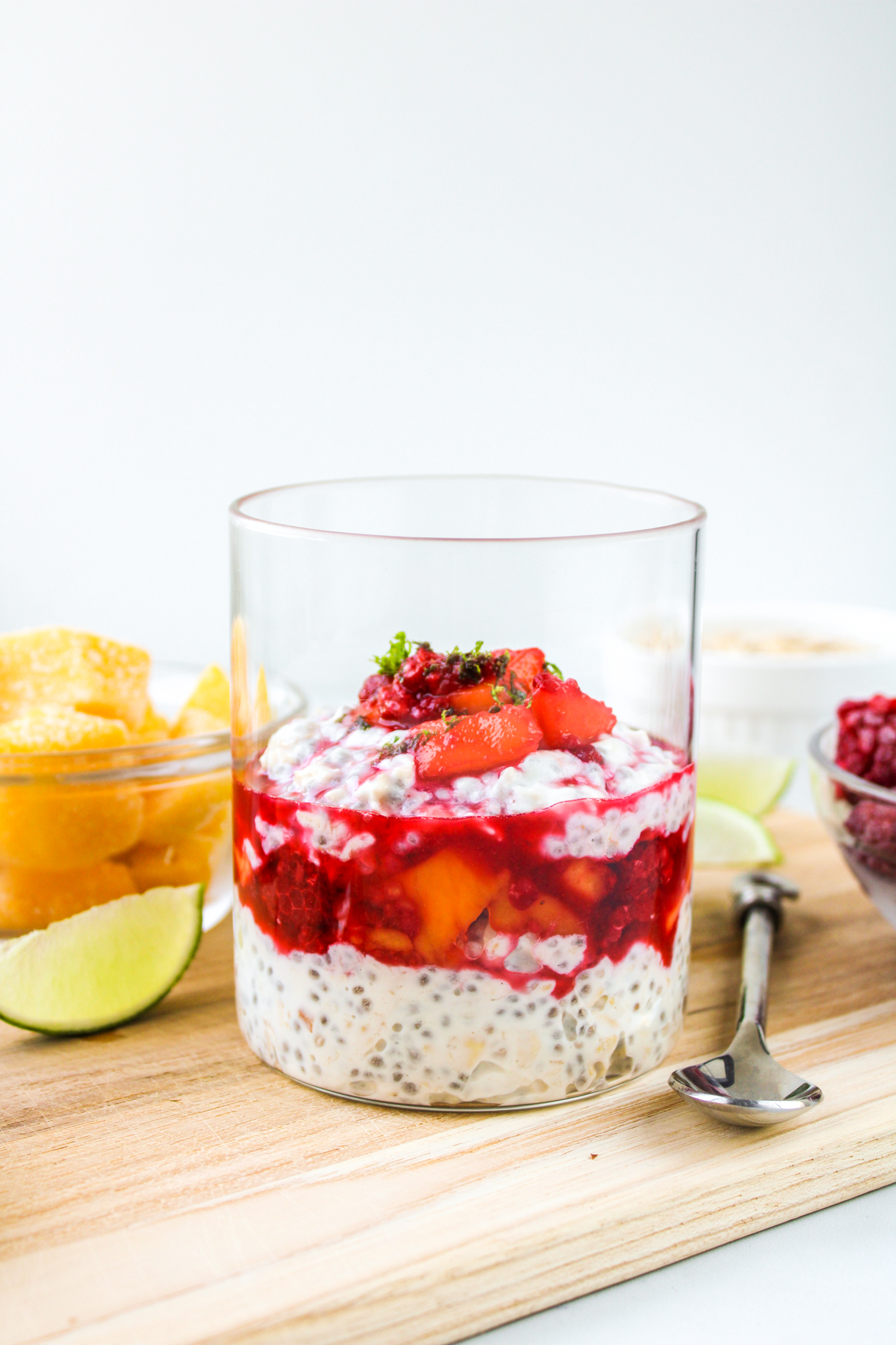 profile shot of mango overnight oats in a glass jar on top of a wooden cutting board
