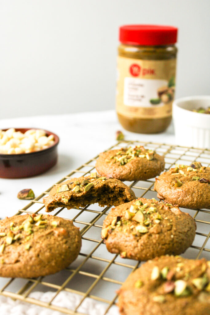 cookies on a cooling rack with pistachio nut butter in the background