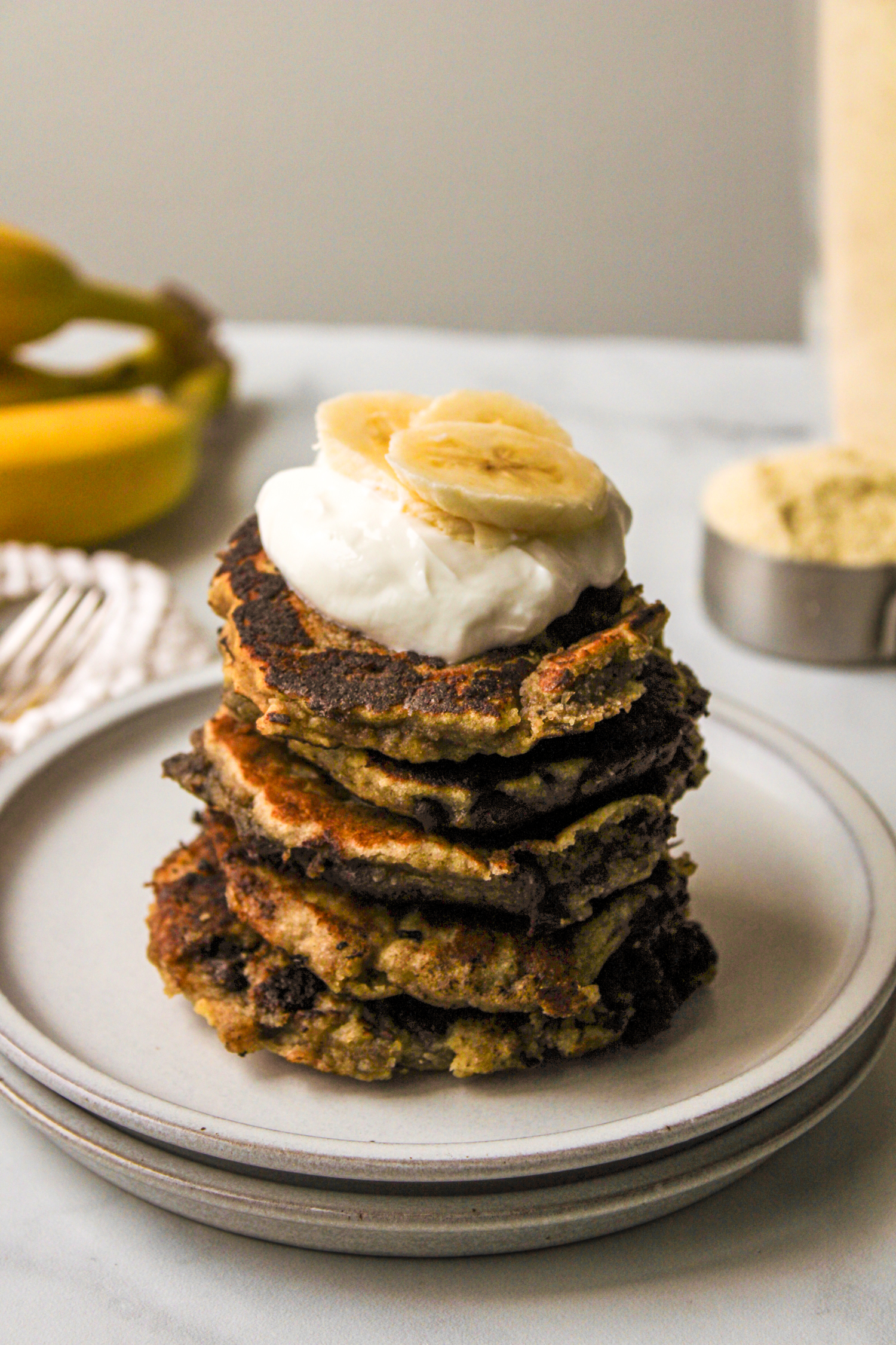 pancakes stacked on top of each other on a white plate with ingredients in the background