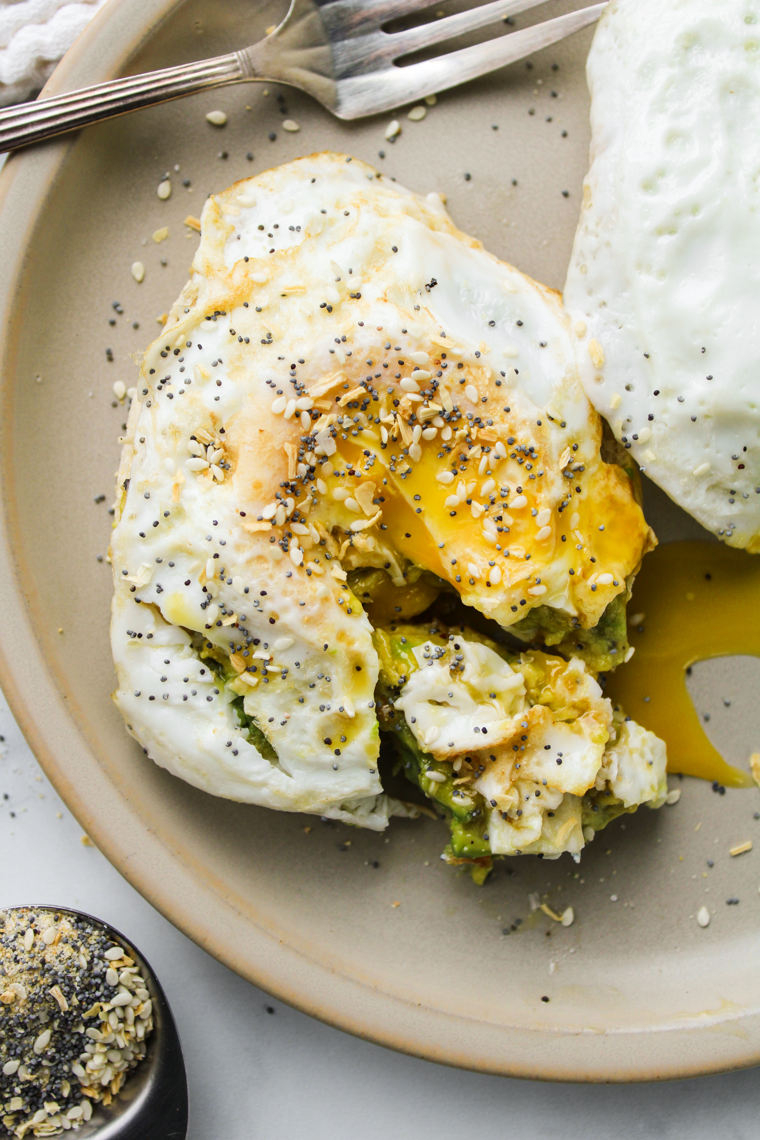 fried egg with everything bagel seasoning on top, placed on a beige ceramic plate