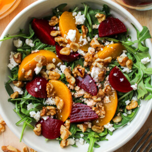 beetroot salad with walnuts and feta in a cream ceramic bowl on top of a wooden board