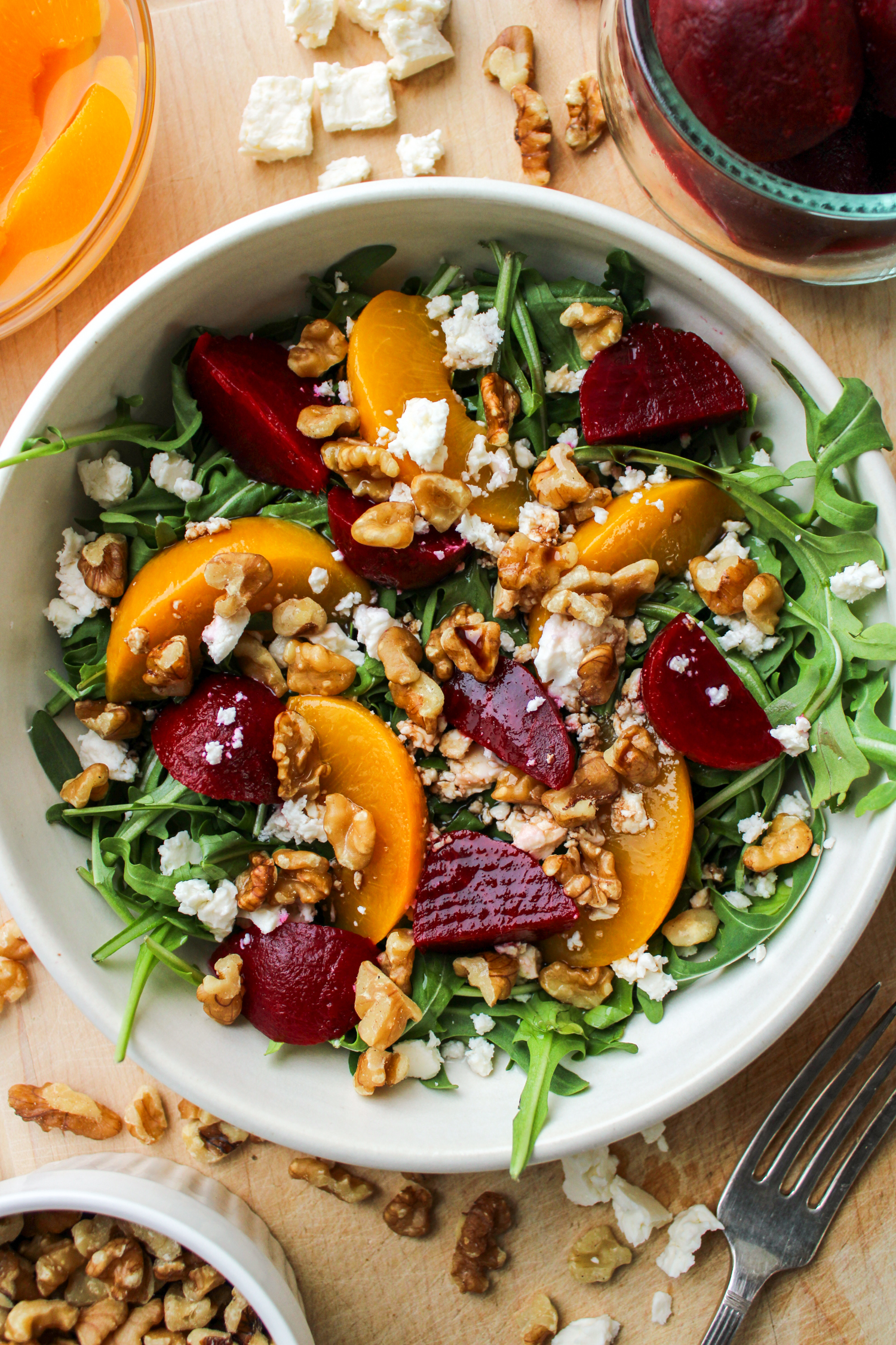 beetroot salad with walnuts and feta in a cream ceramic bowl on top of a wooden board