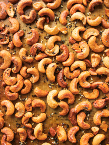 roasted everything bagel cashews on a silicone baking mat on top of a baking sheet