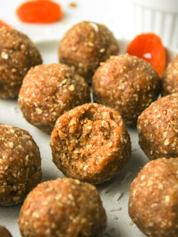 apricot and coconut balls with a bite out of the one in the middle