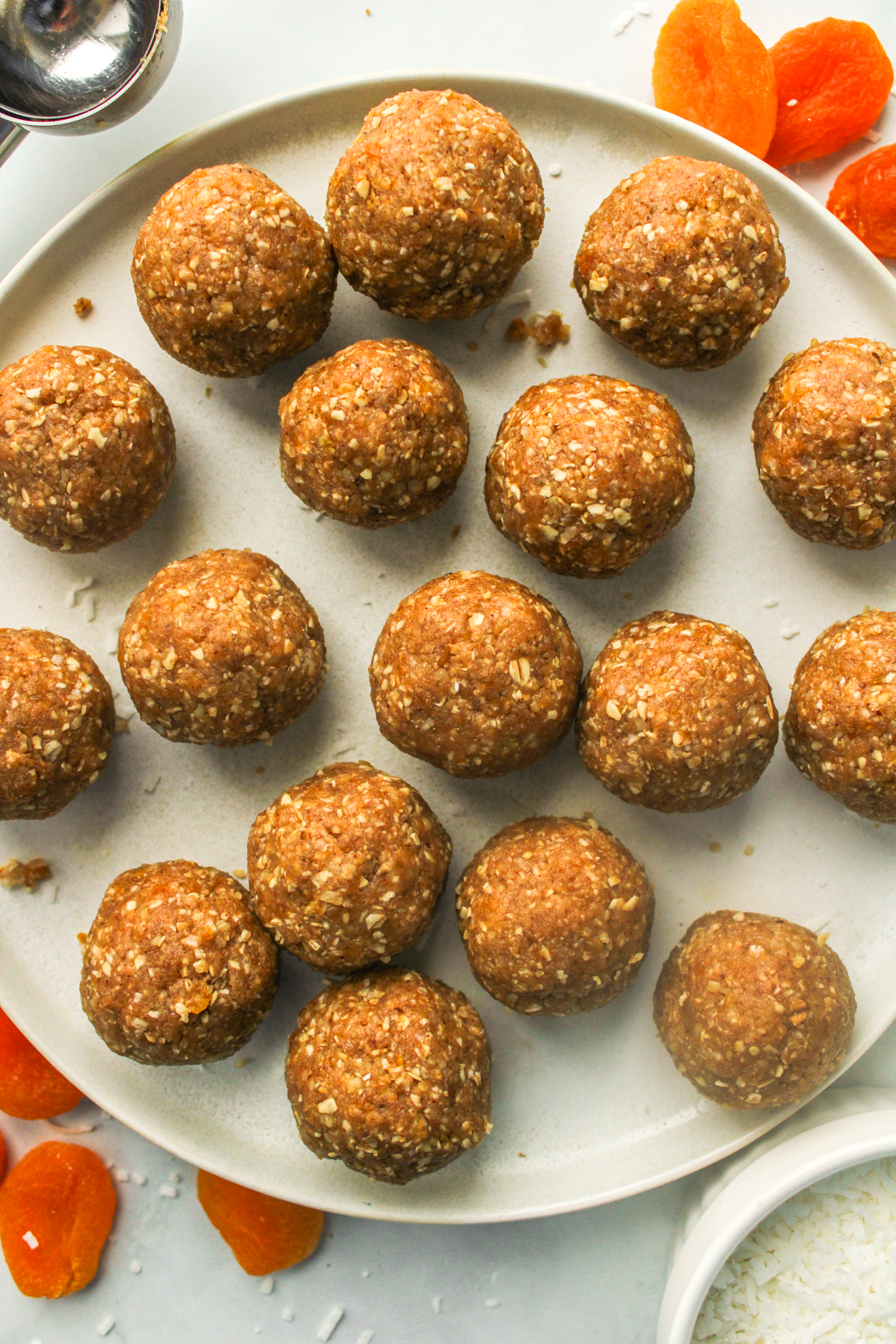 overhead shot of apricot and coconut balls laid out on top of a white ceramic plate