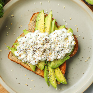 avocado toast with cottage cheese on top of grey ceramic plate