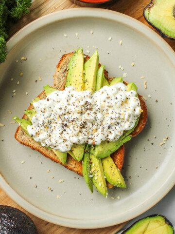 avocado toast with cottage cheese on top of grey ceramic plate
