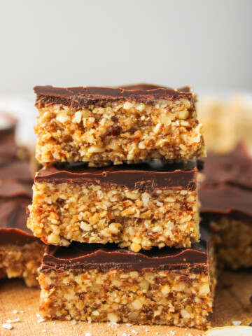 3 squares of cashew bar with chocolate coating stacked on top of each other, profile shot
