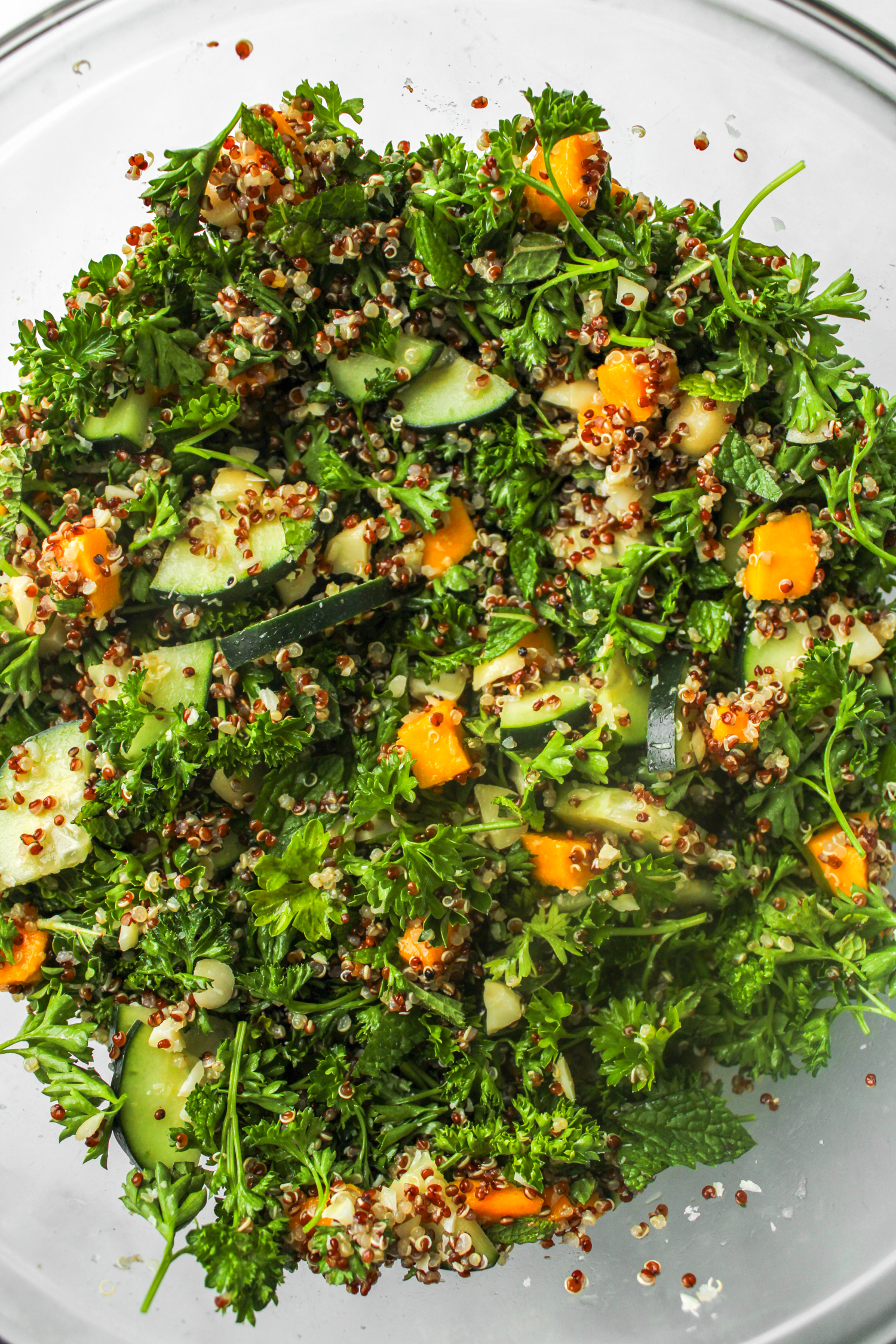 ingredients for the parsley quinoa salad added to a large glass bowl and mixed together