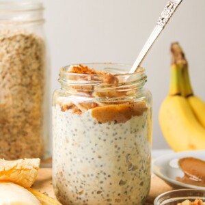banana chia overnight oats in a glass jar, topped with peanut butter, banana and cinnamon