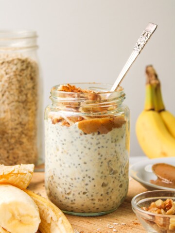 banana chia overnight oats in a glass jar, topped with peanut butter, banana and cinnamon