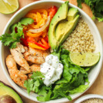 chicken quinoa bowls in a white ceramic dish on top of a wooden cutting board