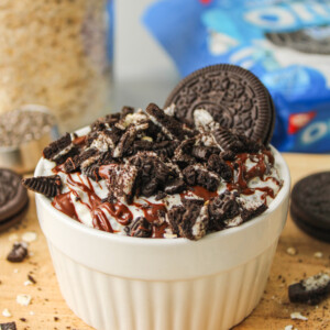oreo overnight oats in a white ceramic dish topped with melted chocolate and oreo crumbs