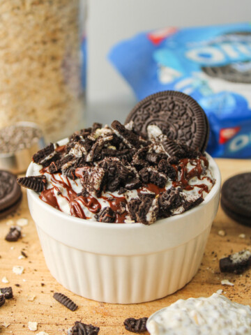 oreo overnight oats in a white ceramic dish topped with melted chocolate and oreo crumbs