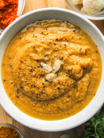cauliflower pumpkin soup in white ceramic bowl topped with pumpkin seeds