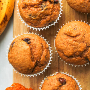 pumpkin banana bread muffins in white paper muffin liners on a wooden board