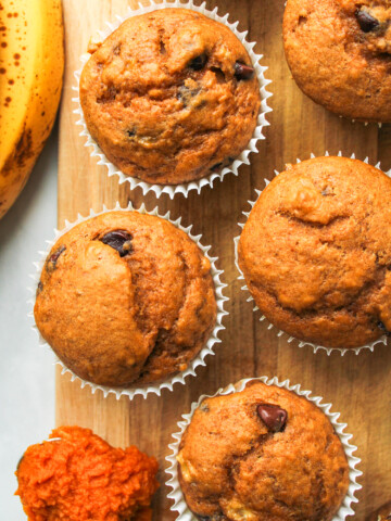 pumpkin banana bread muffins in white paper muffin liners on a wooden board