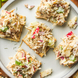 apple walnut chicken salad on top of crackers placed on a grey ceramic plate