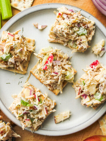 apple walnut chicken salad on top of crackers placed on a grey ceramic plate