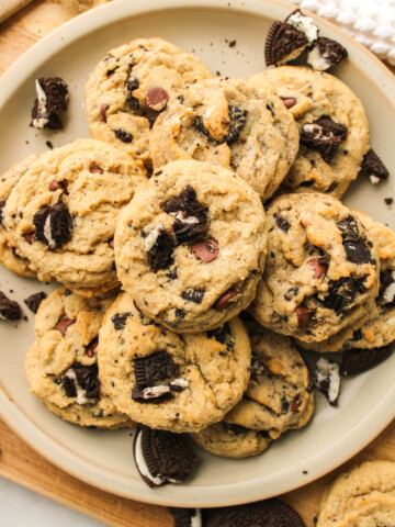 oreo and chocolate chips cookies piled on top of each other on a ceramic plate