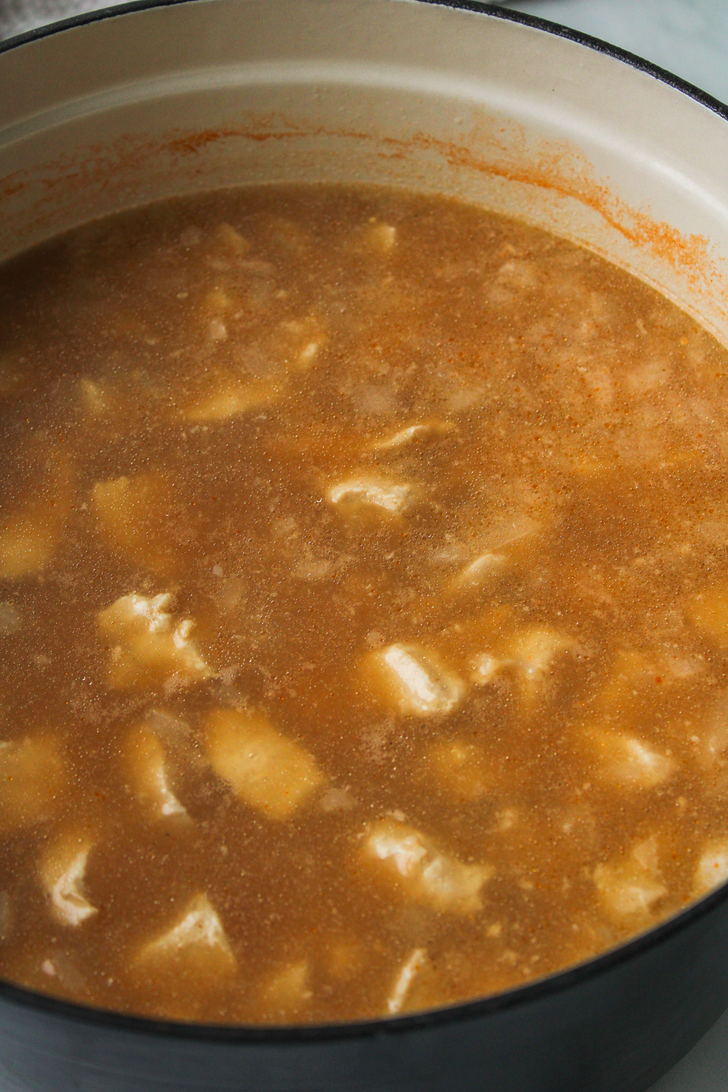 cooked chicken, orzo and vegetable broth in a large ceramic cooking pot