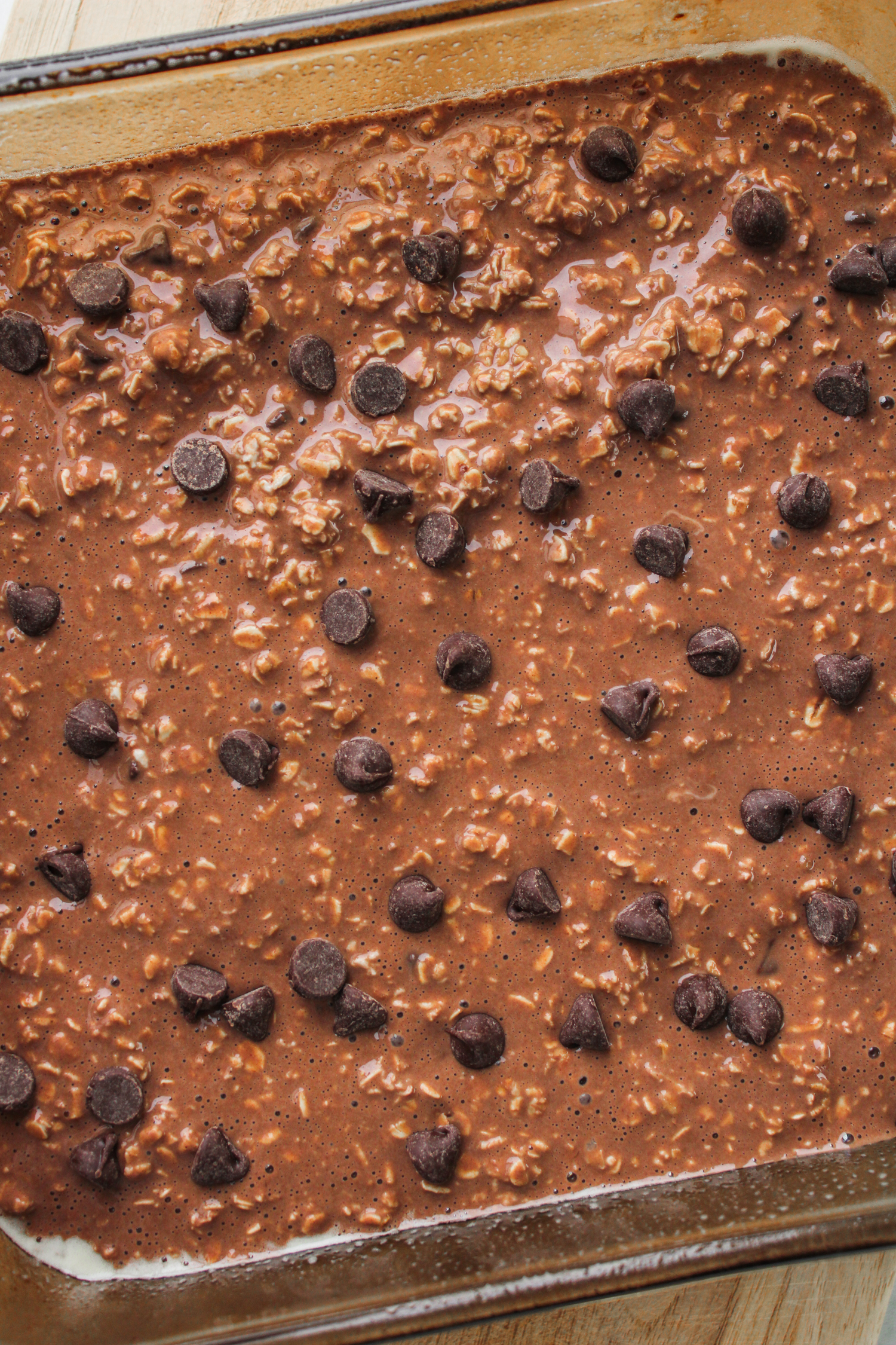unbaked chocolate oatmeal batter in an 8x8" pyrex dish topped with chocolate chips