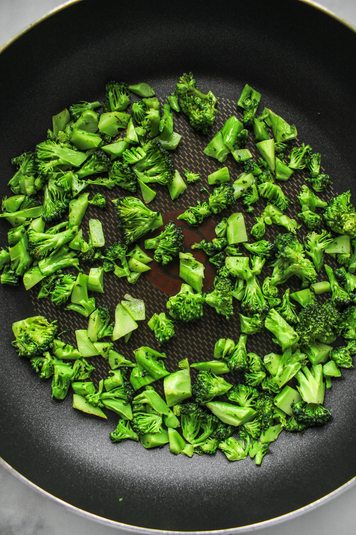 finely chopped broccoli sauteing in a large black pain