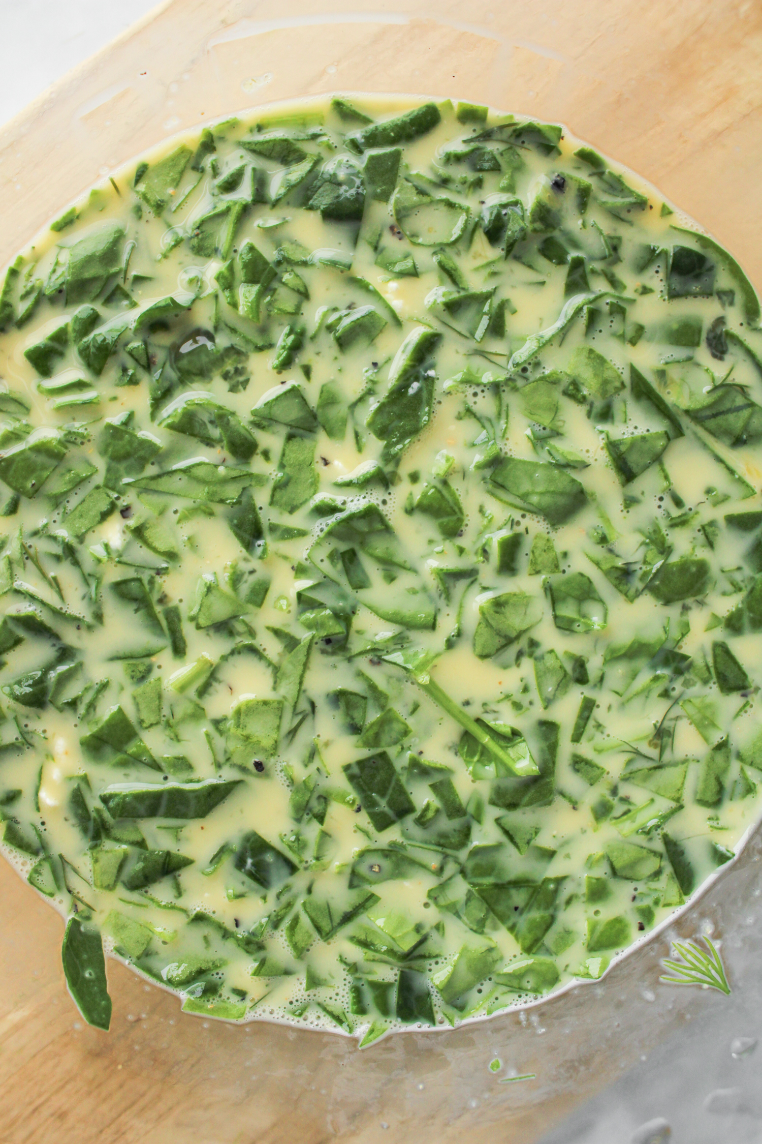 egg mixture with spinach and herbs in a large glass bowl
