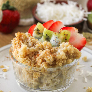 close up shot of quinoa coconut milk porridge in a small glass bowl topped with kiwi and strawberries