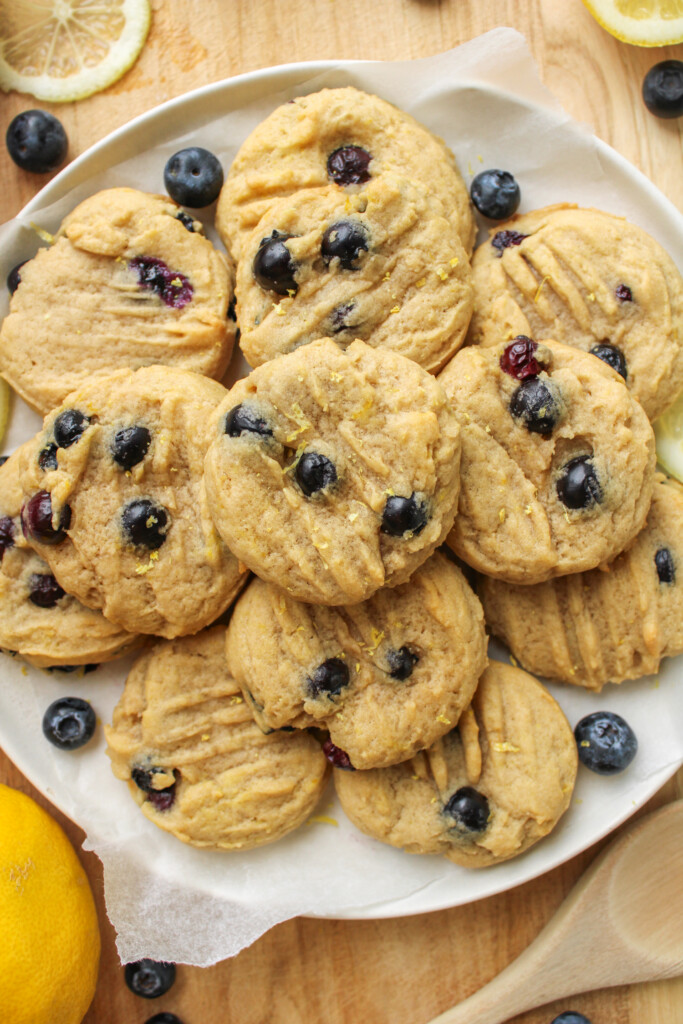 overhead shot of lemon blueberry cookies stacked on top of a white ceramic plate