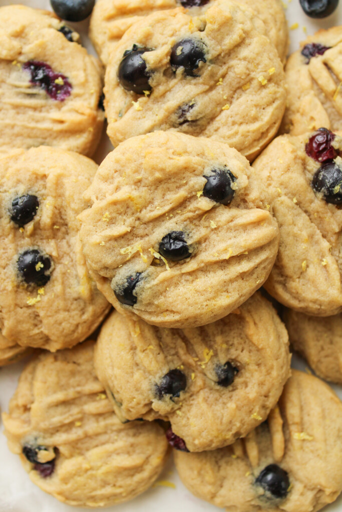 zoomed in overhead shot of lemon blueberry cookies stacked on top of a white ceramic plate