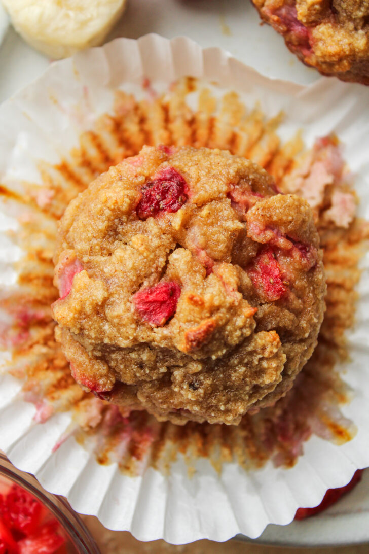 overhead shot of a banana strawberry muffin on a muffin liner