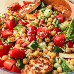 chickpea and halloumi salad with chili oil vinaigrette in a large bowl with wooden serving spoon