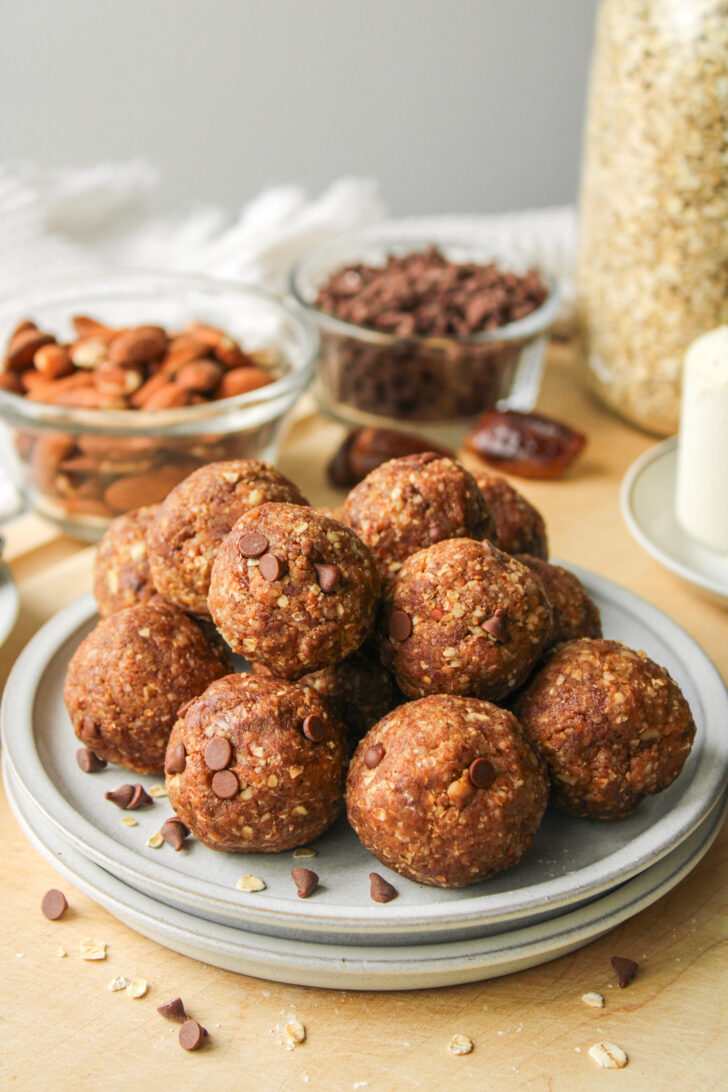 cookie dough protein balls stacked on top of each other on grey ceramic plates on top of a wooden board