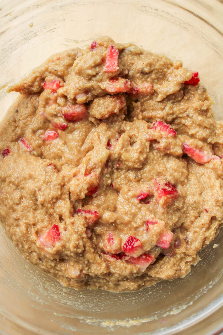raw muffin batter with strawberries in a large glass bowl