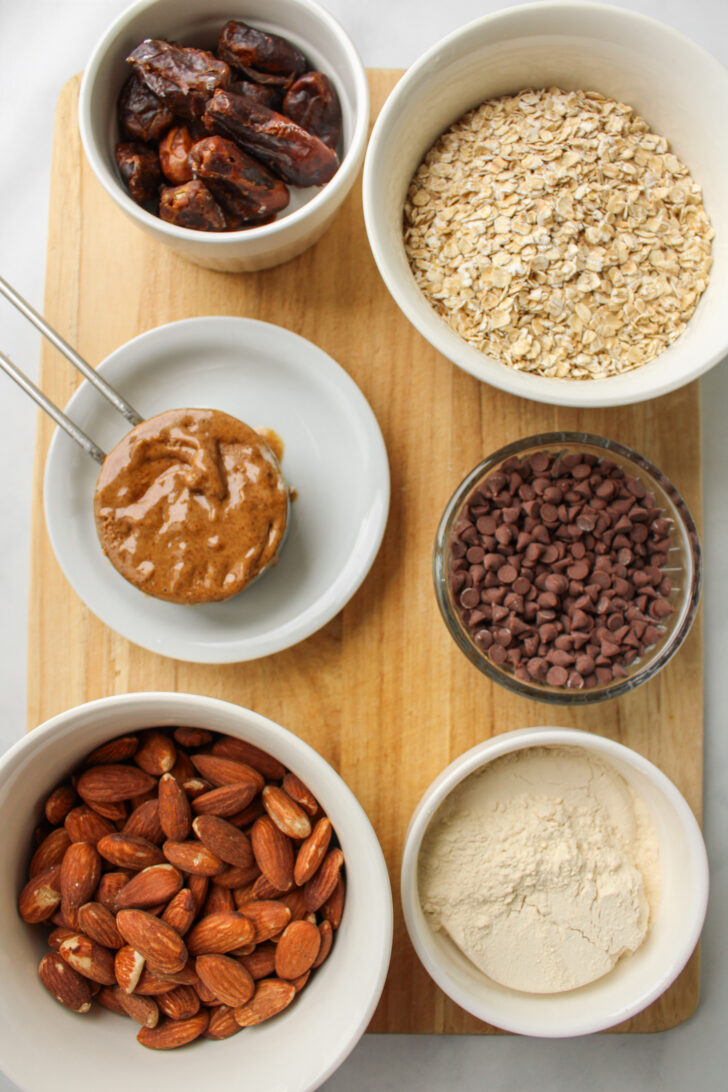 protein ball ingredients laid out on a wooden cutting board