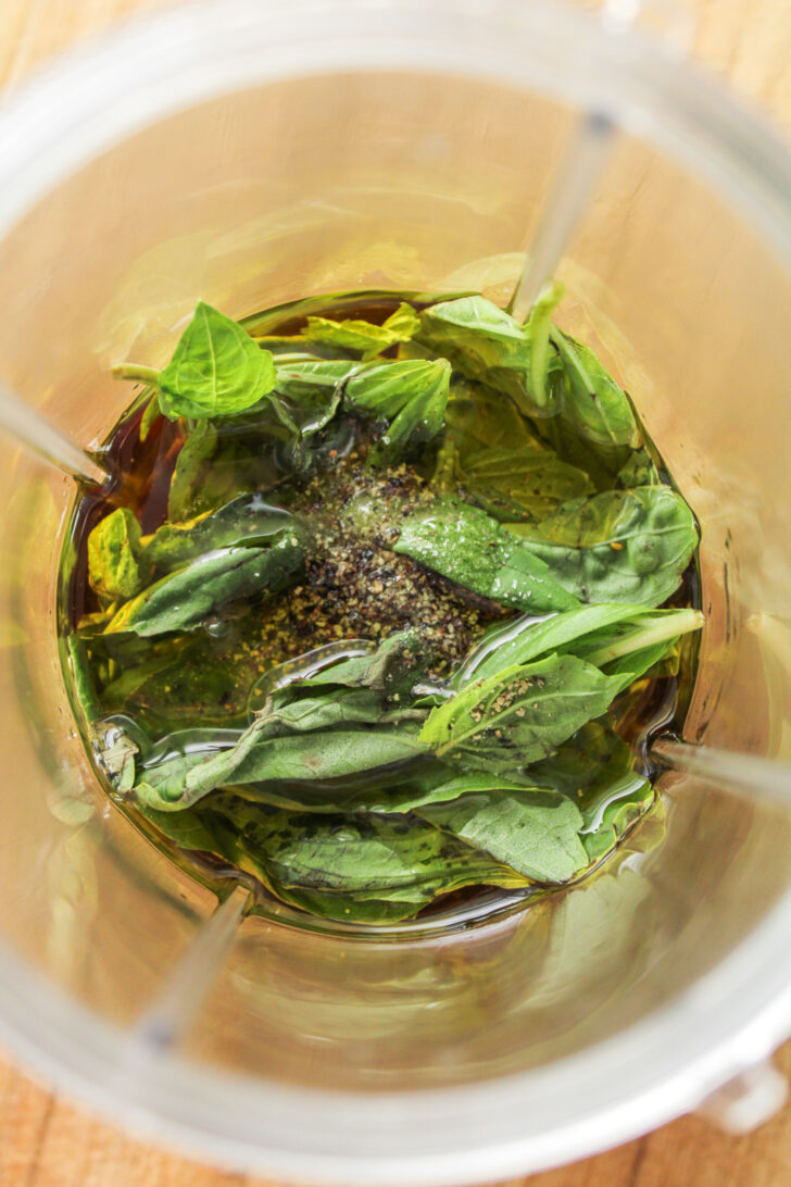 overhead shot of basil in olive oil in a blender cup