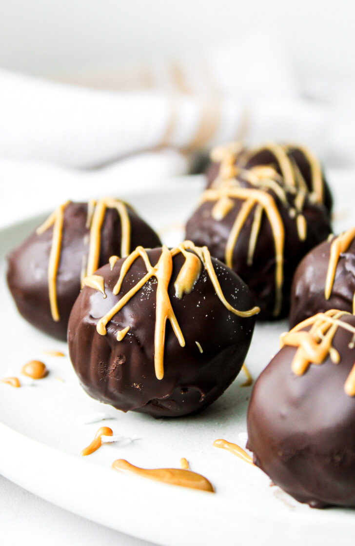 profile shot of chocolate and peanut butter protein balls on a grey ceramic plate