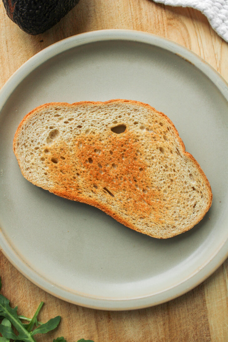 plain toast on a ceramic plate on top of a wooden cutting board