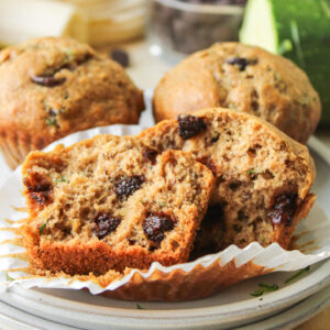 a banana zucchini chocolate chip muffin in half on top of stacked ceramic plates
