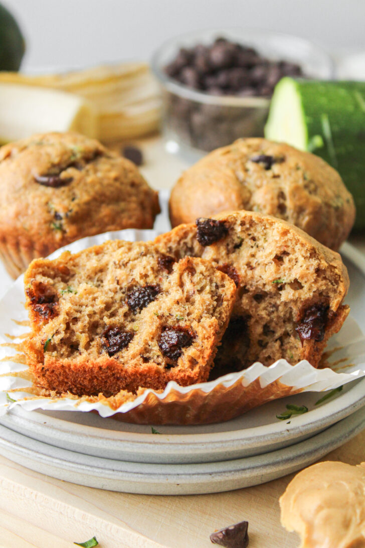 a banana zucchini chocolate chip muffin in half on top of stacked ceramic plates
