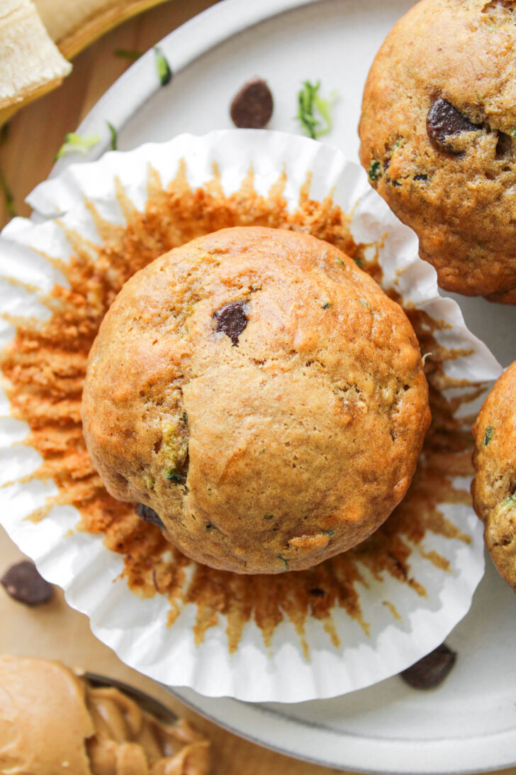 an overhead close up of banana zucchini chocolate chip muffin on top of the paper liner