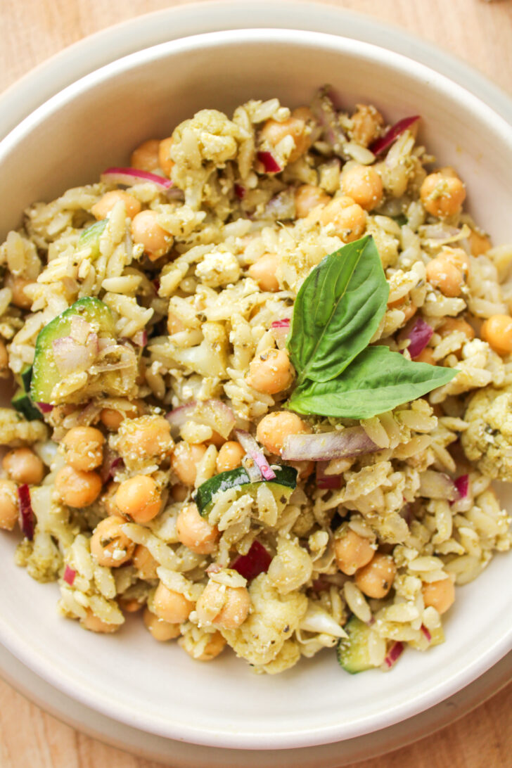 overhead shot of orzo pesto pasta salad in a white ceramic bowl