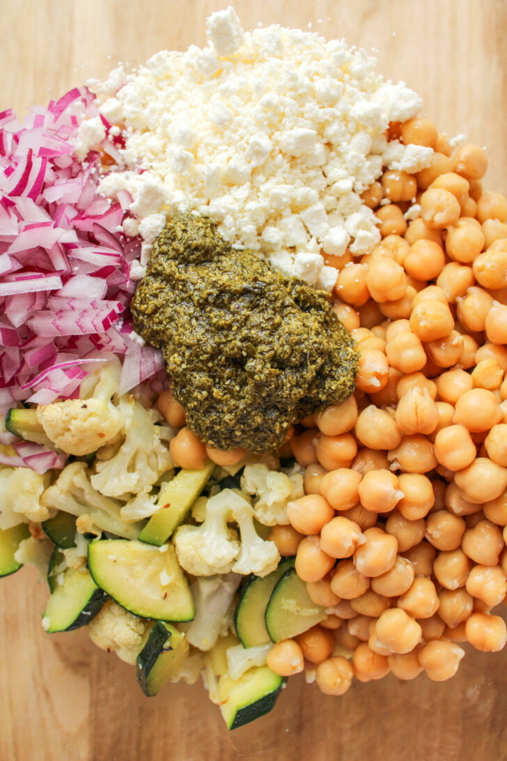 orzo pasta salad ingredients in a large glass bowl before getting mixed together