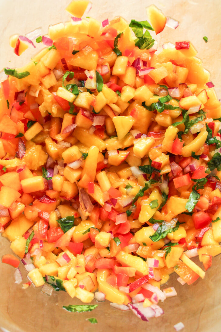 overhead shot of peach mango salsa mixed together in a large glass bowl